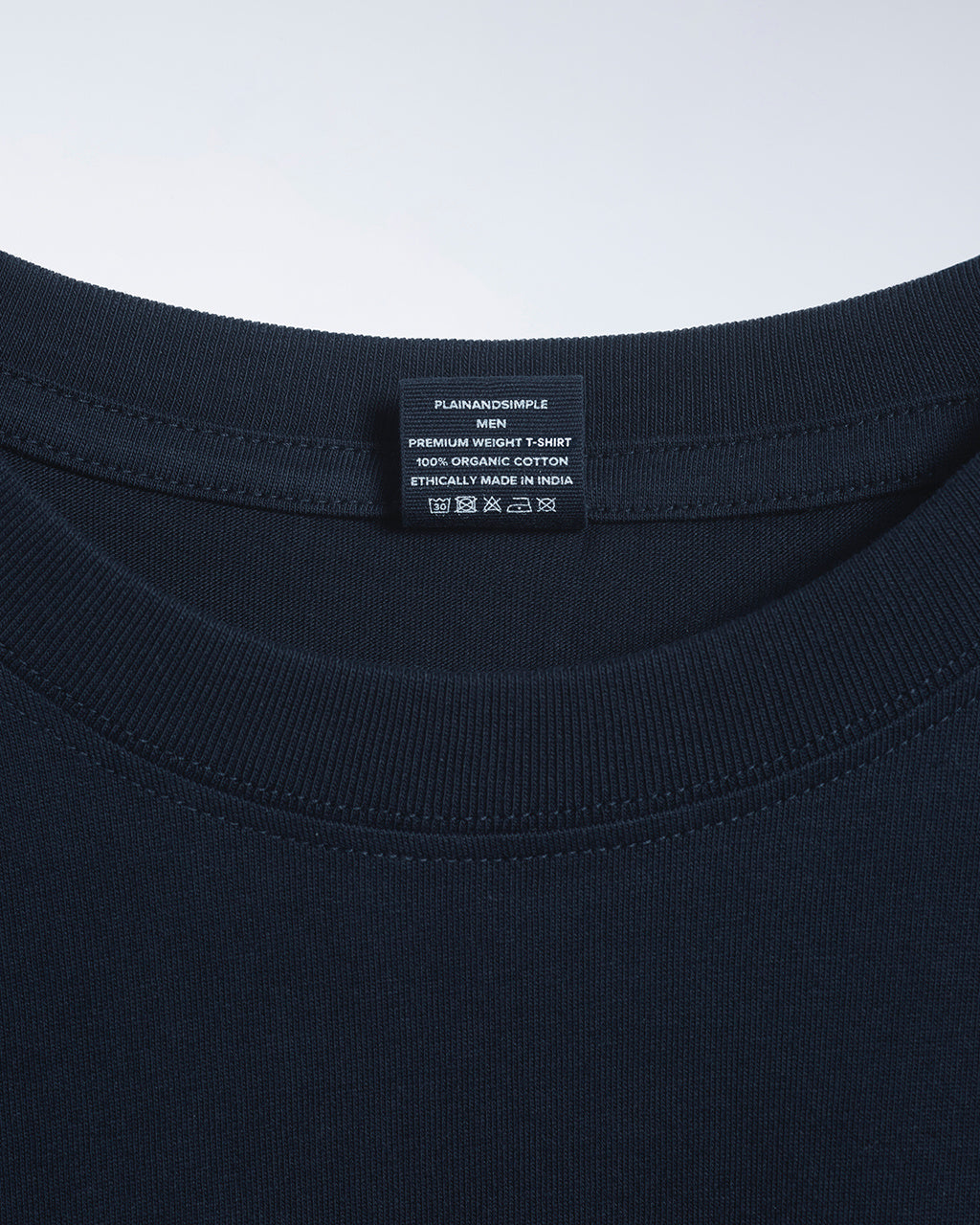 A close up of an neck label in a men's navy short sleeve crew neck organic cotton t shirt.
