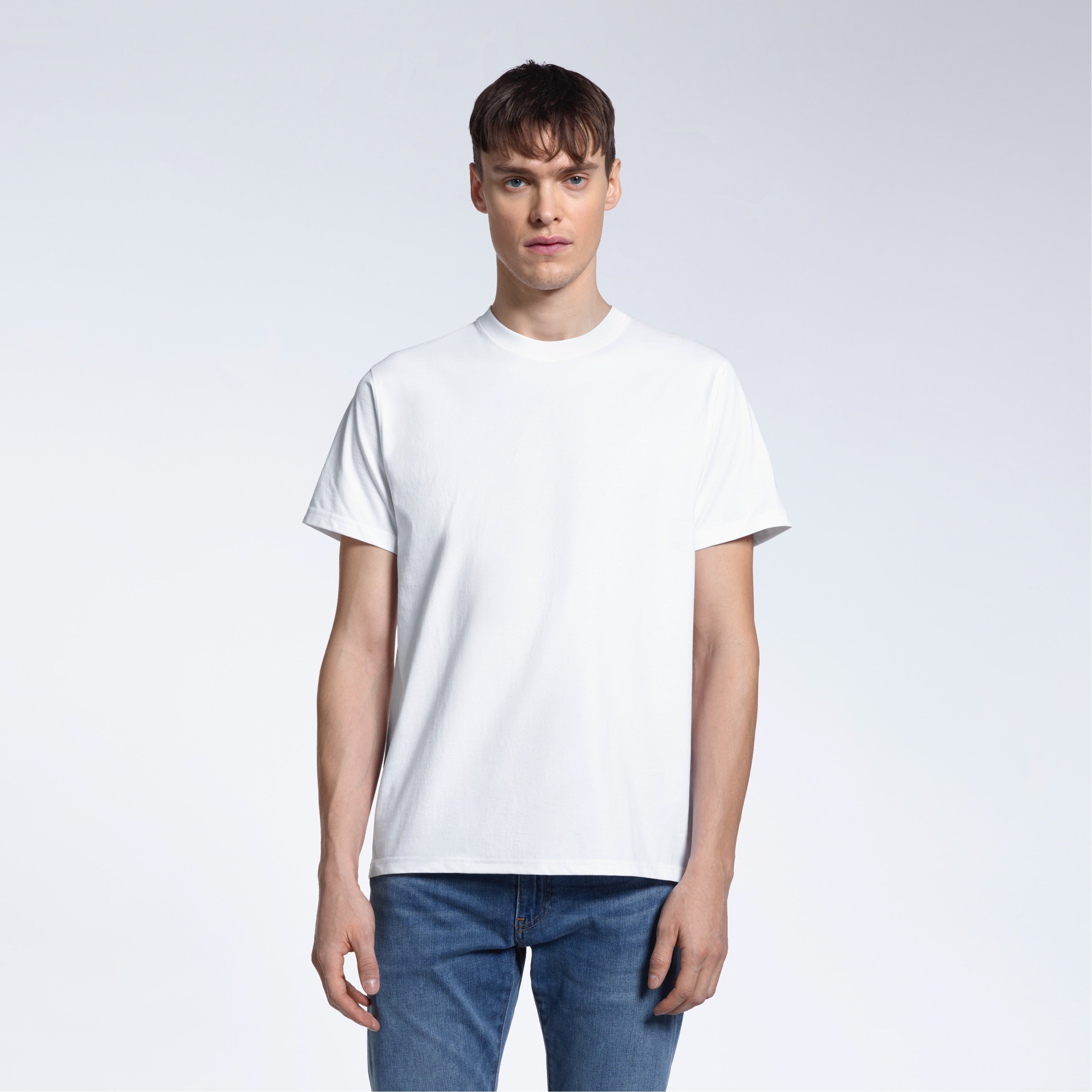 A man facing front on looking into the camera, modelling a plain white short sleeve organic cotton t shirt.