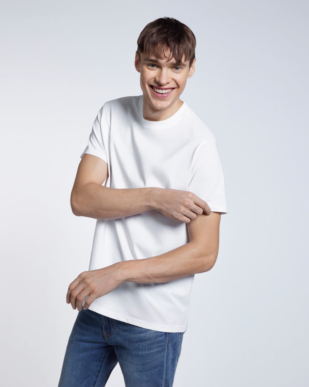 A man smiling touching his sleeve, modelling a plain white short sleeve organic cotton t shirt.