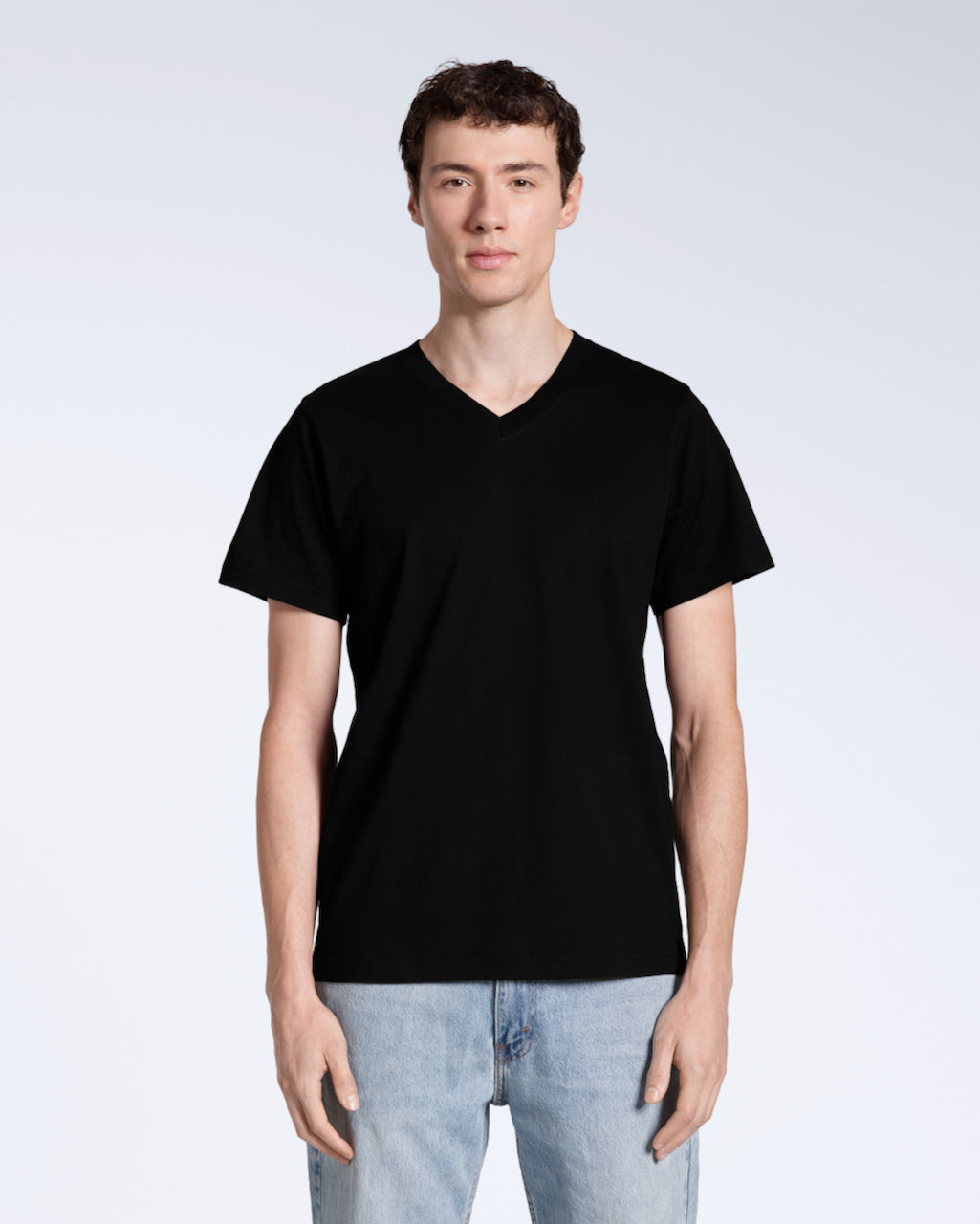 A man facing front on, looking into the camera with his arms by his side, modelling a plain black, organic cotton v neck t shirt.