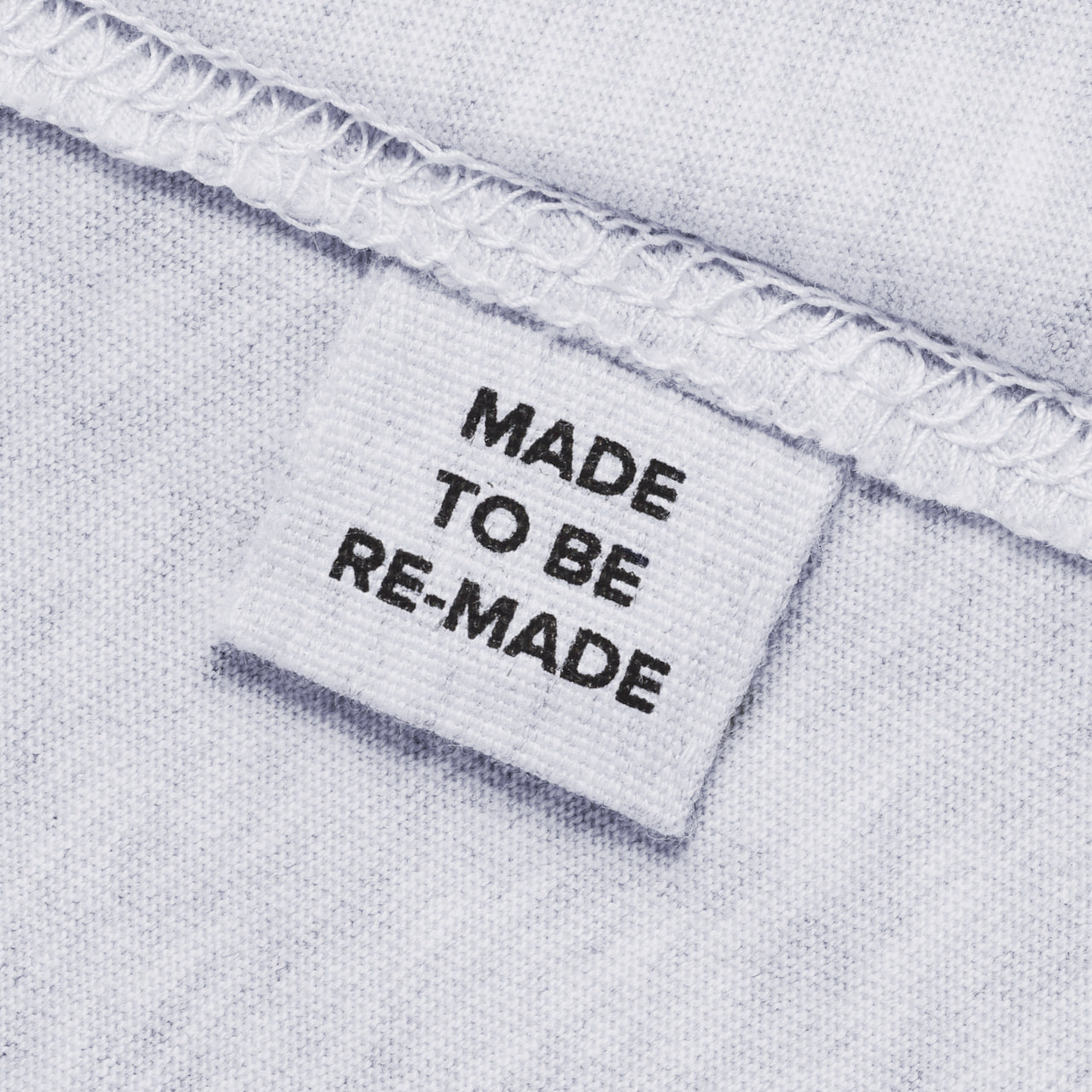 A close up of a label tag in a grey organic cotton hoodie that says 'made to be re made'.