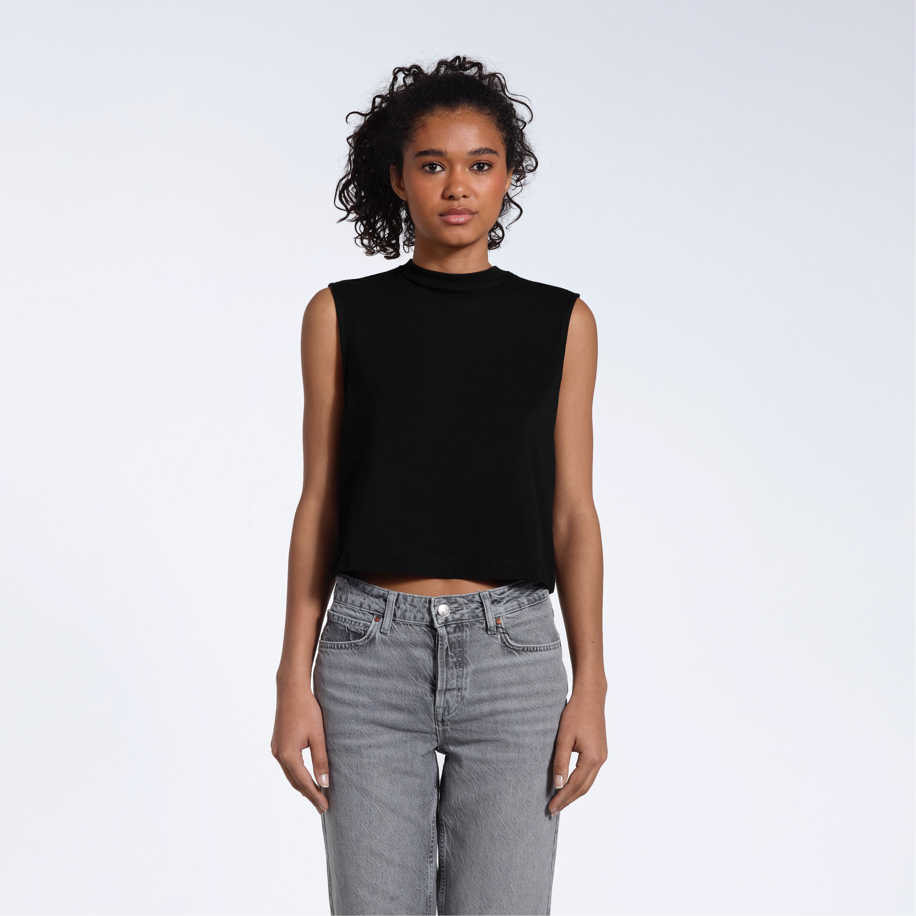 A woman facing front on looking at the camera, modelling a black short sleeve organic cotton tank top.