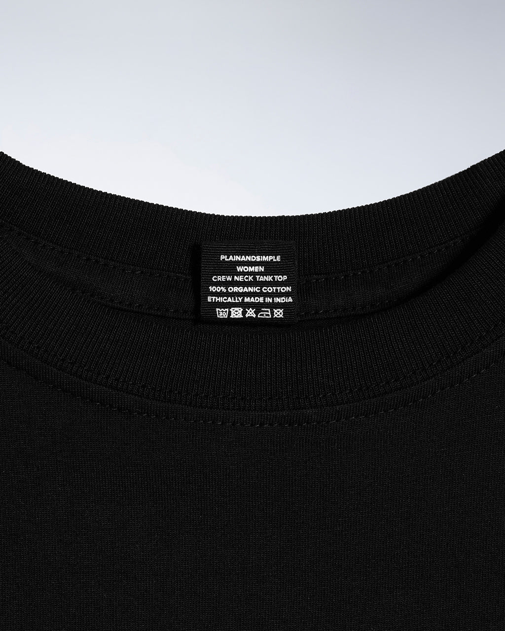 A close up of a neck label in a women's black sleeveless organic cotton crew neck tank top.