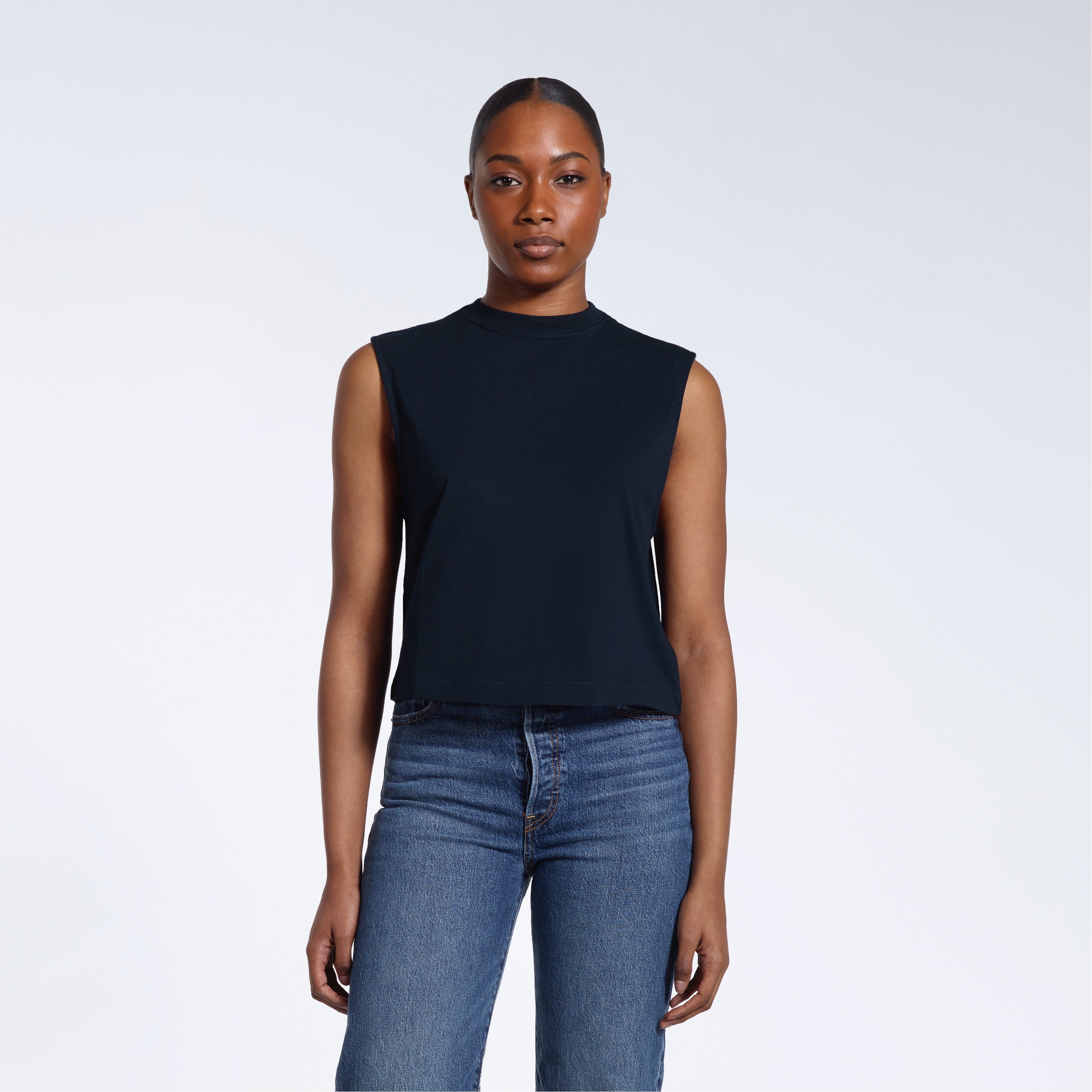 A woman facing front on looking at the camera, modelling a navy sleeveless organic cotton tank top.