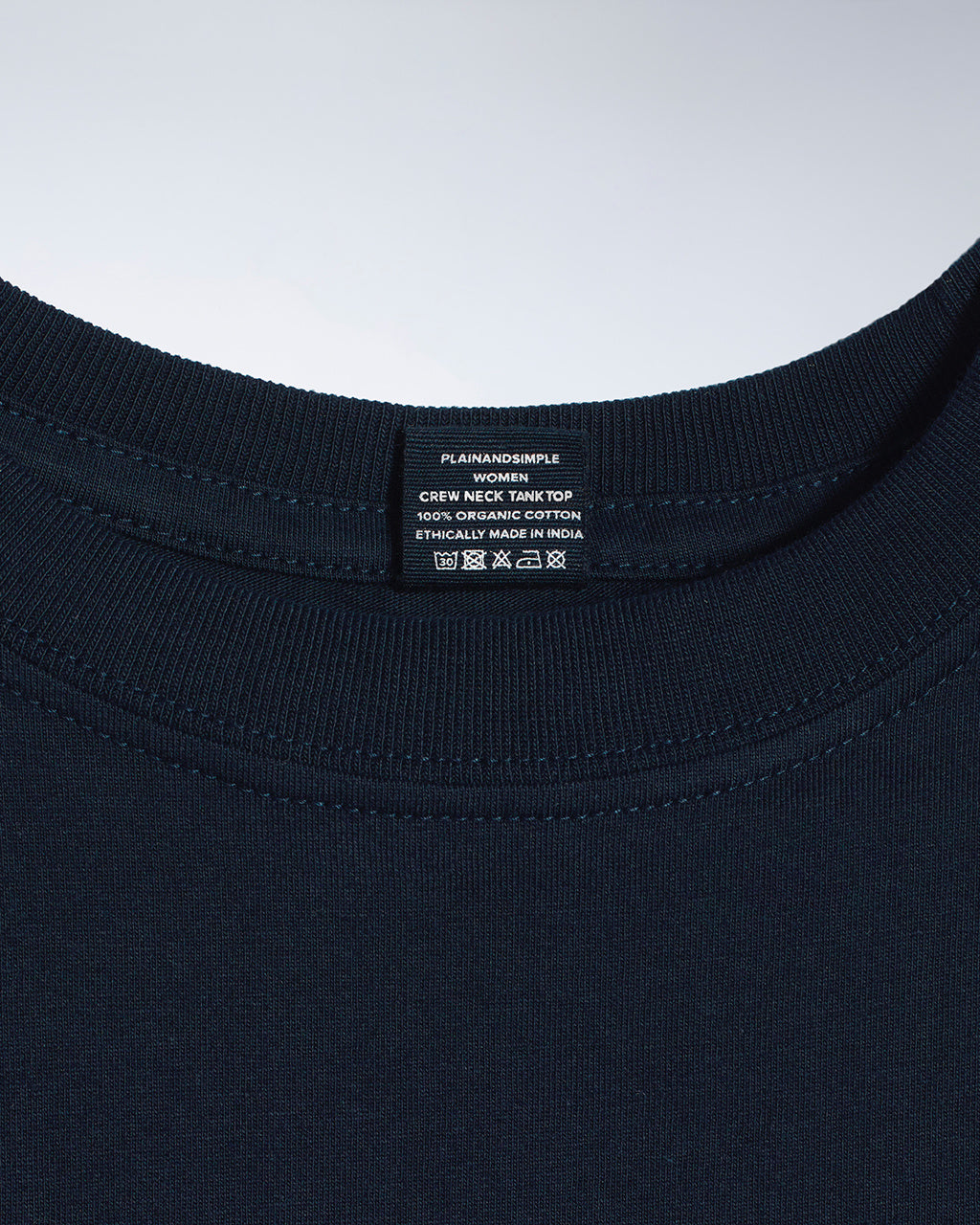 A close up of a neck label in a women's navy sleeveless organic cotton crew neck tank top.