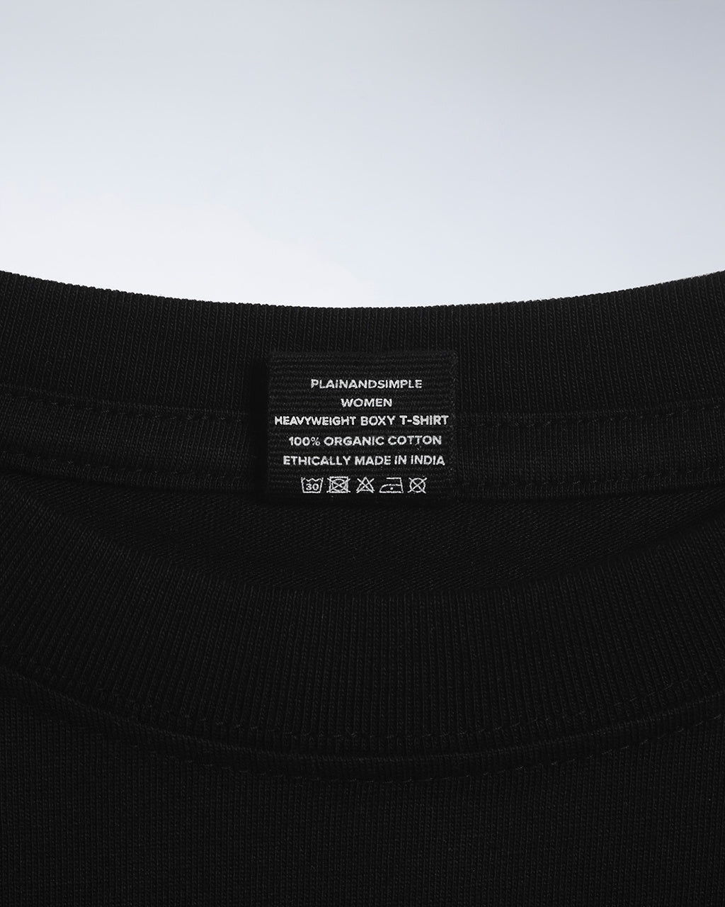 A close up of an neck label in a women's black boxy crew neck heavyweight organic cotton t shirt.