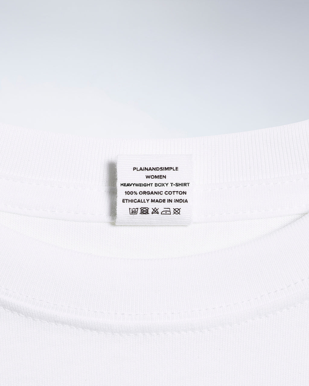 A close up of an neck label in a women's white boxy crew neck heavyweight organic cotton t shirt.