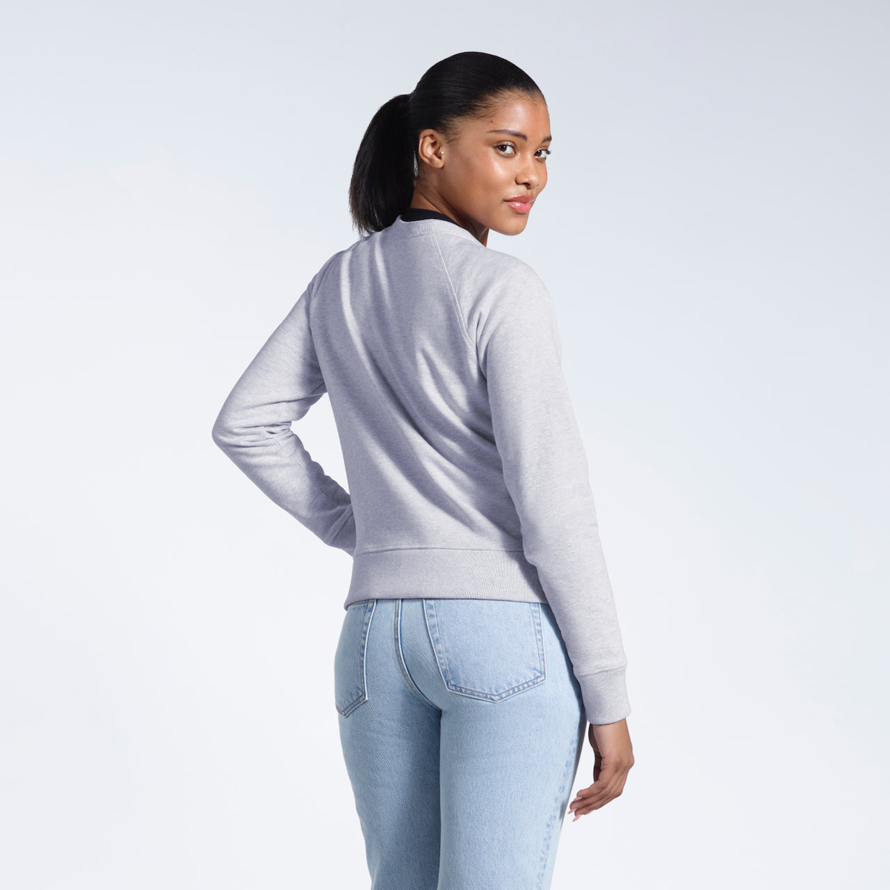 A woman looking back at the camera, showing the back of her grey heavyweight organic cotton sweatshirt.