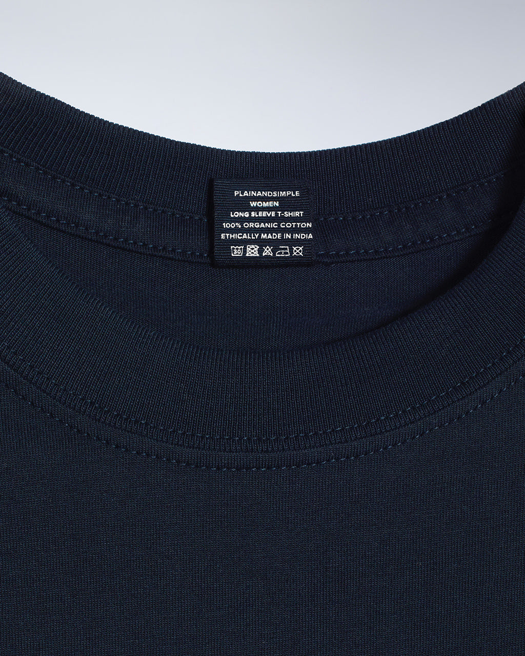 A close up of a neck label in a women's navy long sleeve crew neck organic cotton t shirt.