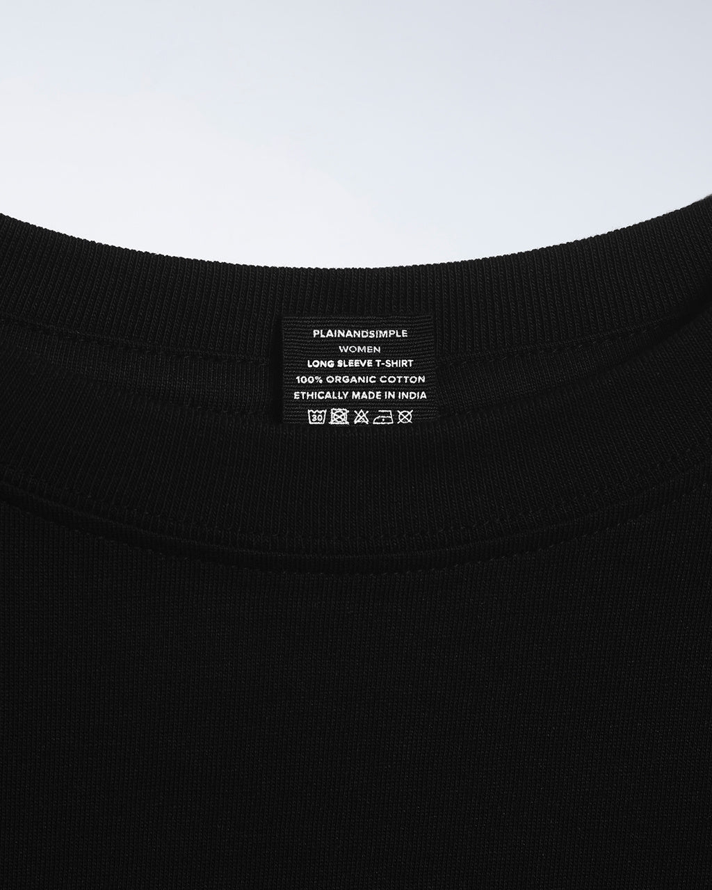 A close up of an neck label in a women's black long sleeve crew neck organic cotton t shirt.
