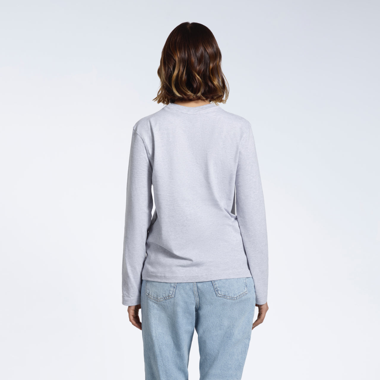 A woman facing away from the camera with her arms by her sides, modelling a plain grey long sleeve organic cotton t shirt.