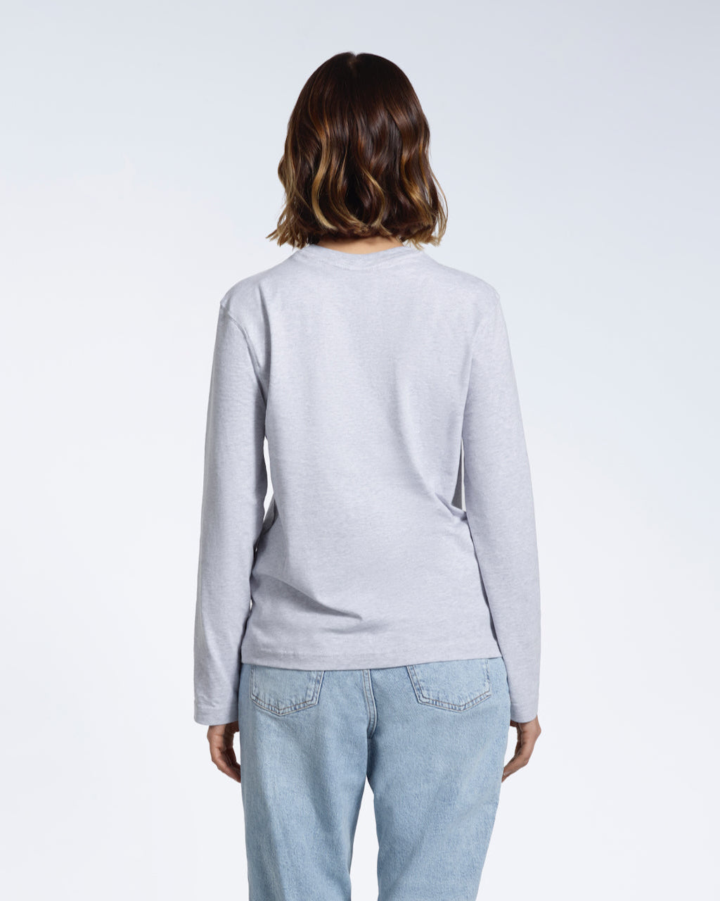 A woman facing away from the camera with her arms by her sides, modelling a plain grey long sleeve organic cotton t shirt.