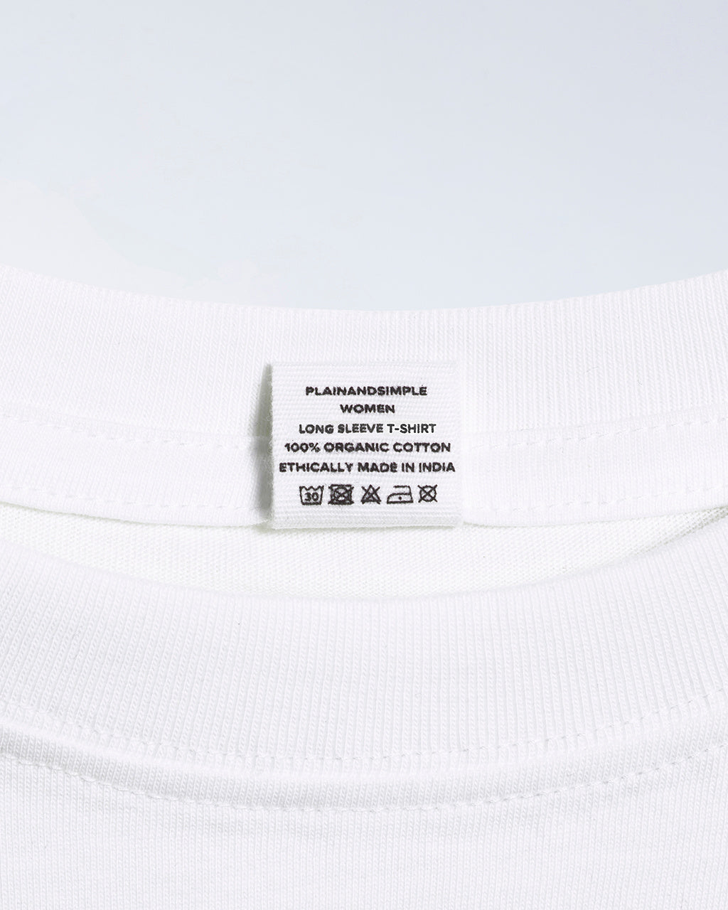 A close up of an neck label in a women's white long sleeve crew neck organic cotton t shirt.