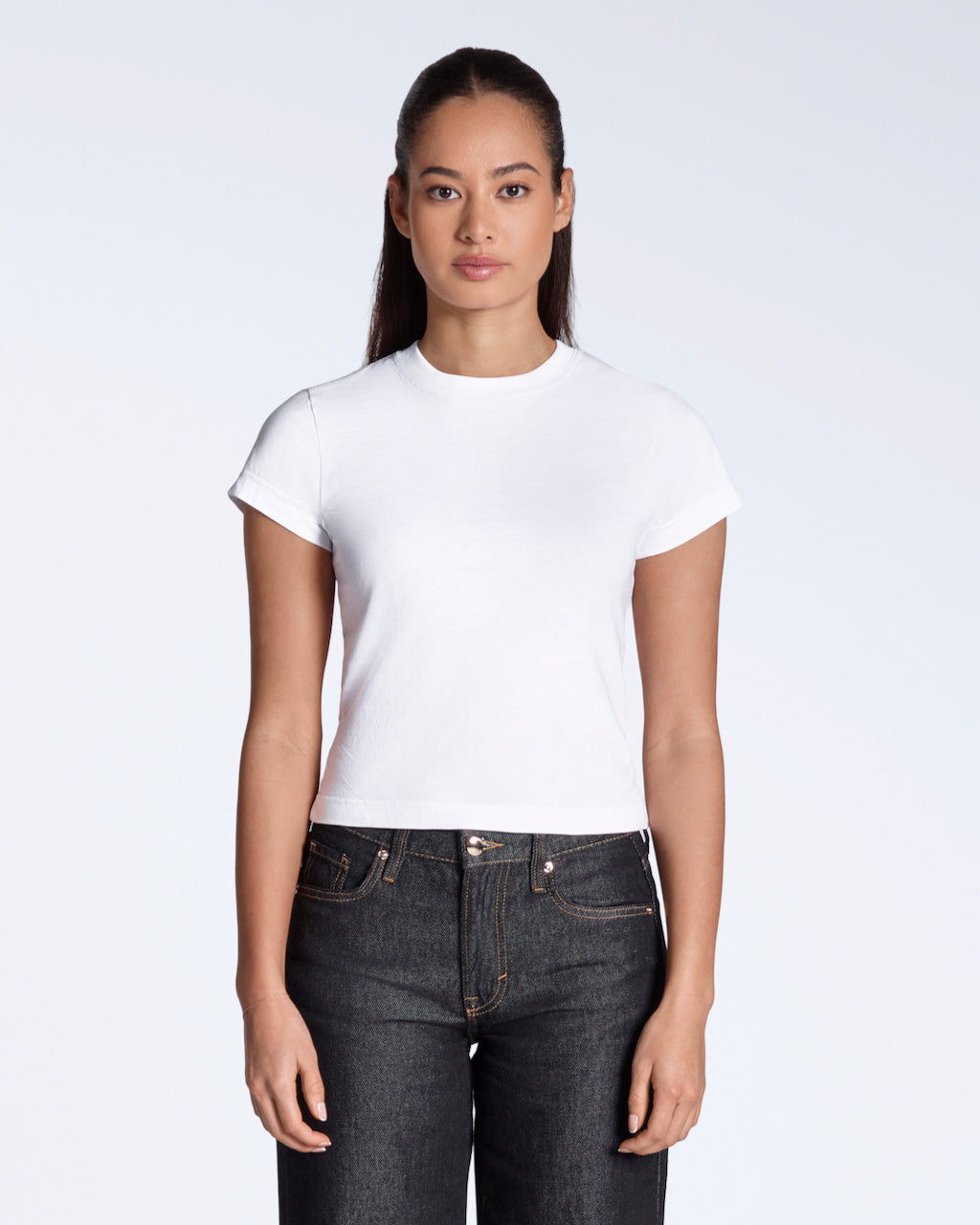 A woman facing front on looking into the camera, modelling a plain white, organic cotton, mini t shirt.
