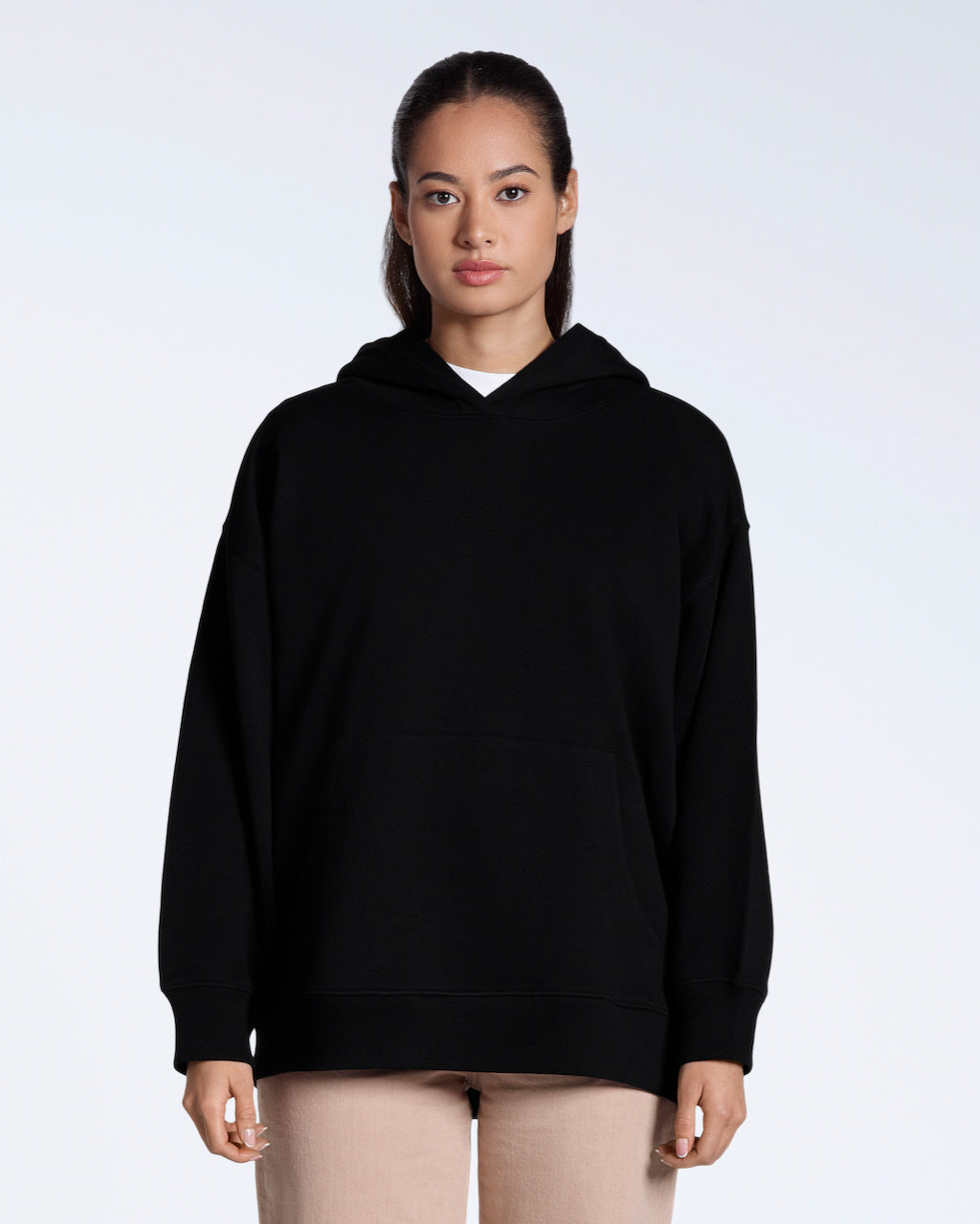 A woman facing front on, modelling a plain black, oversized, organic cotton hoodie.