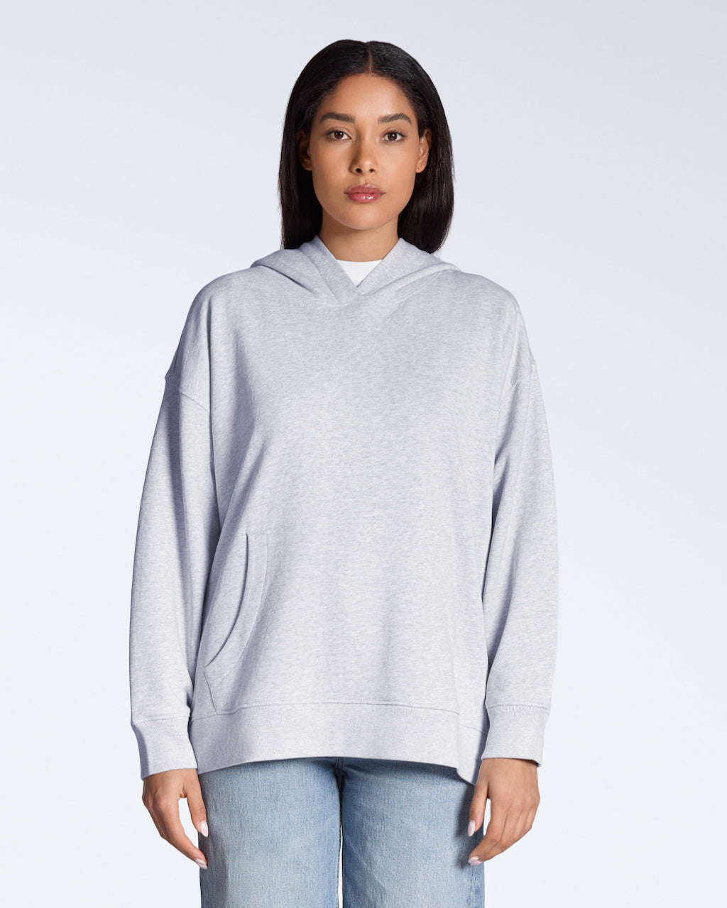 A woman facing front on, modelling a plain grey, oversized, organic cotton hoodie.