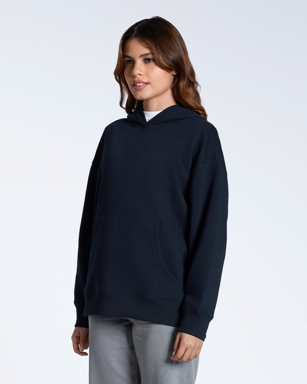 A woman at an angle with her arms by her sides, modelling a plain navy, oversized, organic cotton hoodie.