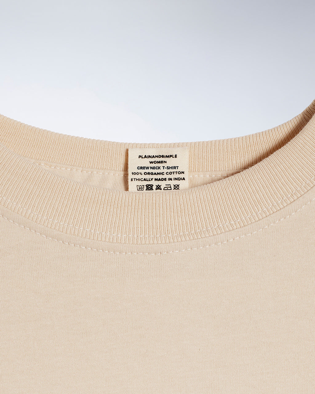 A close up of a neck label in a women's beige short sleeve crew neck organic cotton t shirt.