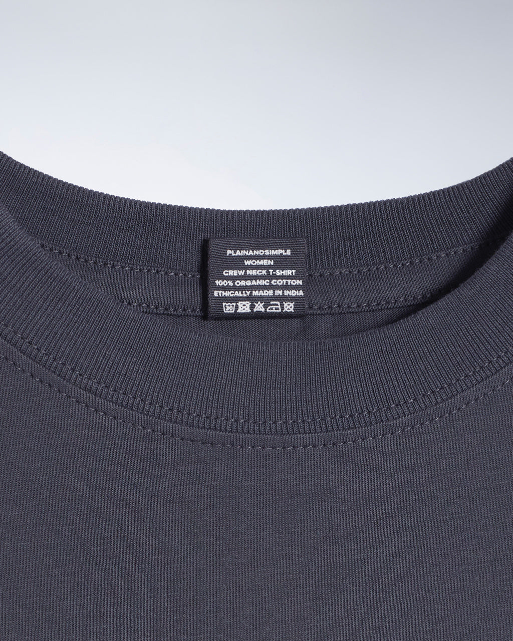 A close up of a neck label in a women's dark grey short sleeve crew neck organic cotton t shirt.