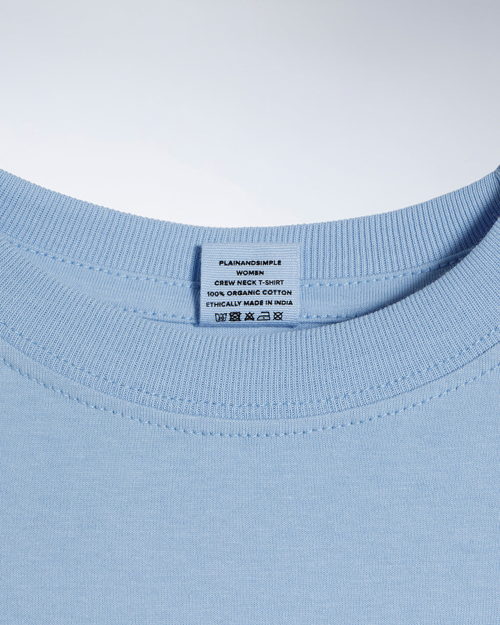 A close up of a neck label in a women's blue short sleeve crew neck organic cotton t shirt.