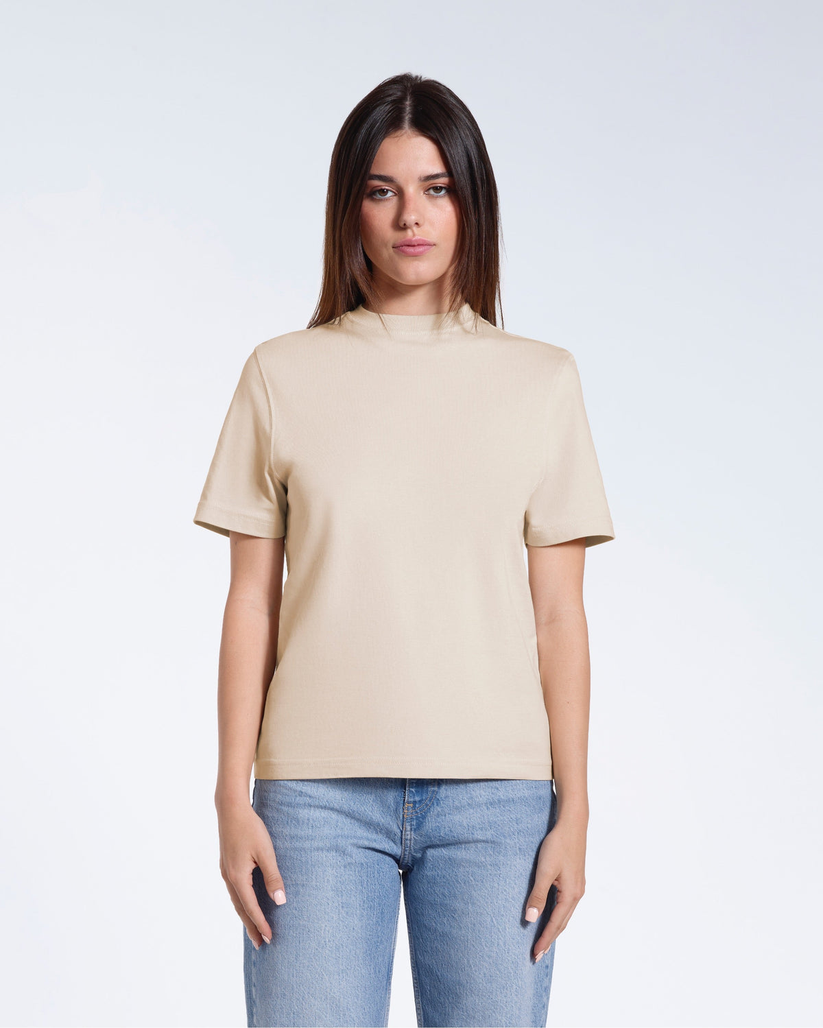 A woman facing front on looking at the camera, modelling a beige short sleeve organic cotton t shirt.