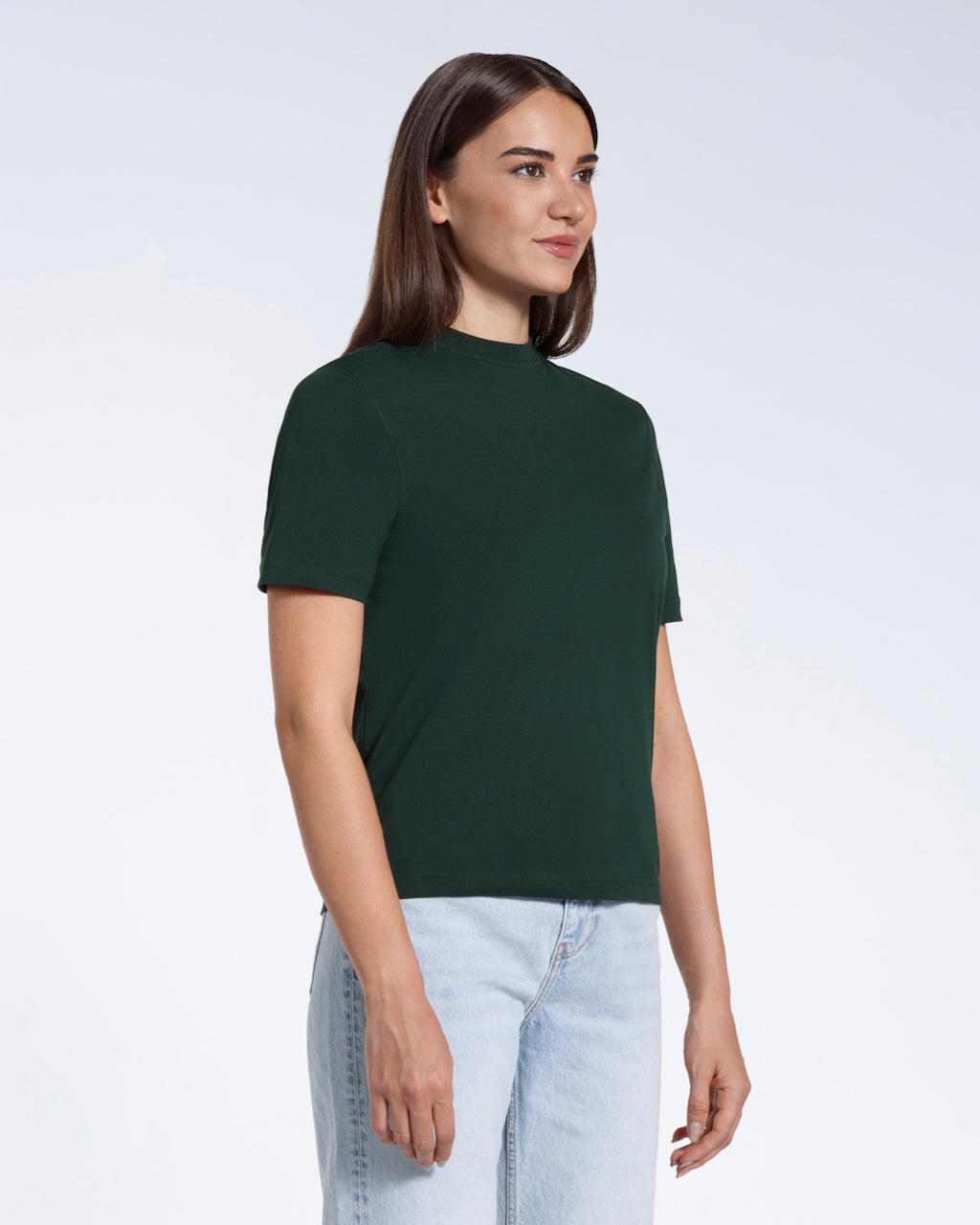 A woman at an angle with her arms at her sides, modelling a plain green short sleeve organic cotton t shirt.