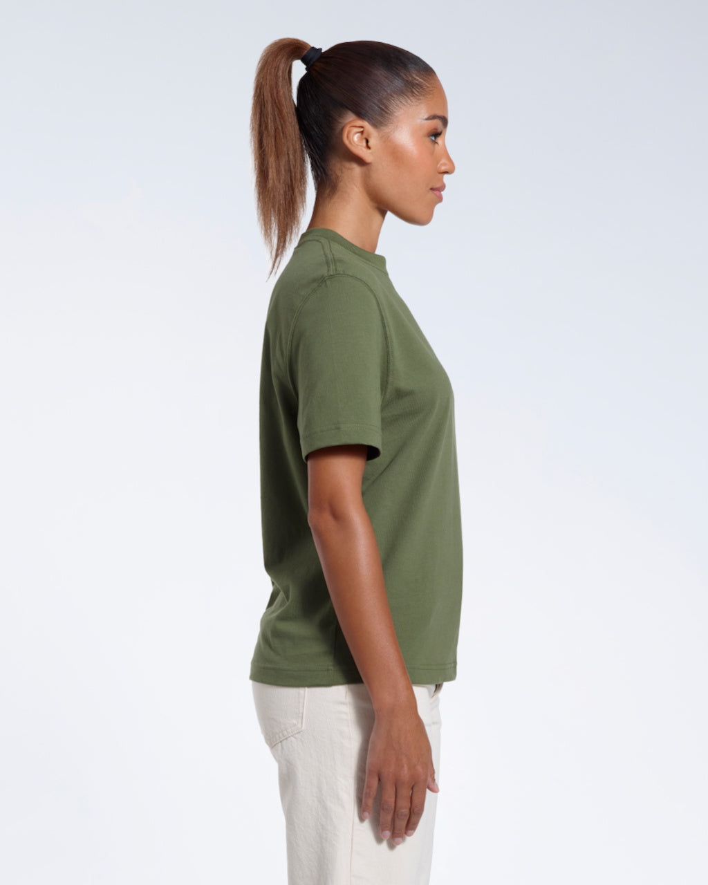 A woman facing side on, modelling a plain khaki green short sleeve organic cotton t shirt.