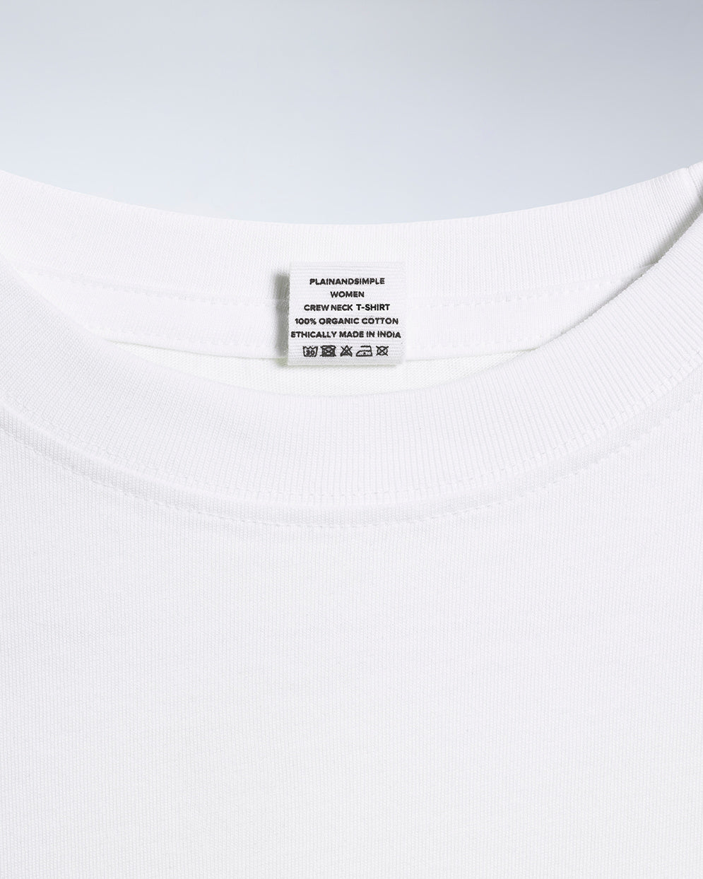 A close up of an neck label in a women's white short sleeve crew neck organic cotton t shirt.