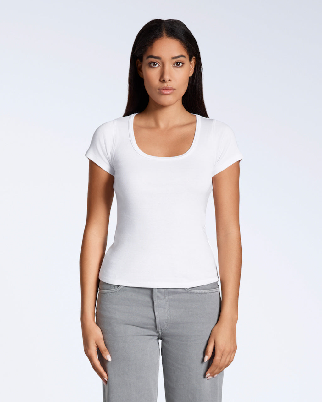 A woman facing front on, looking into the camera with her arms by her side, modelling a plain white, organic cotton scoop neck t shirt.