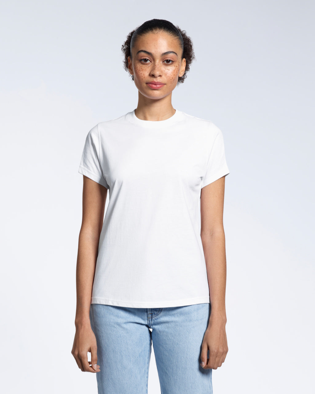 A woman facing front on looking into the camera, modelling a plain white short sleeve organic cotton t shirt.