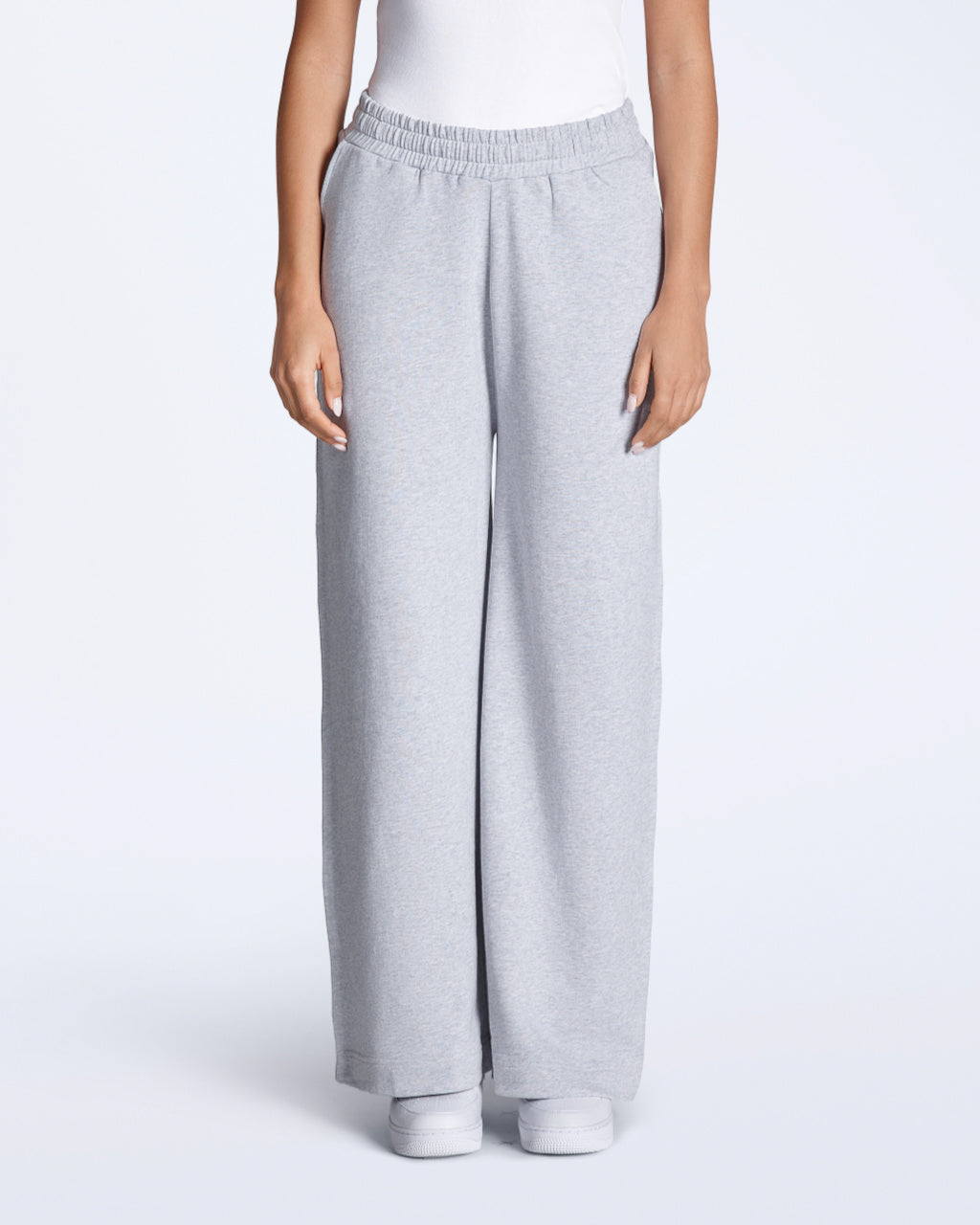 A woman facing front on with her hands by her sides, modelling a pair of grey, organic cotton, wide leg joggers.