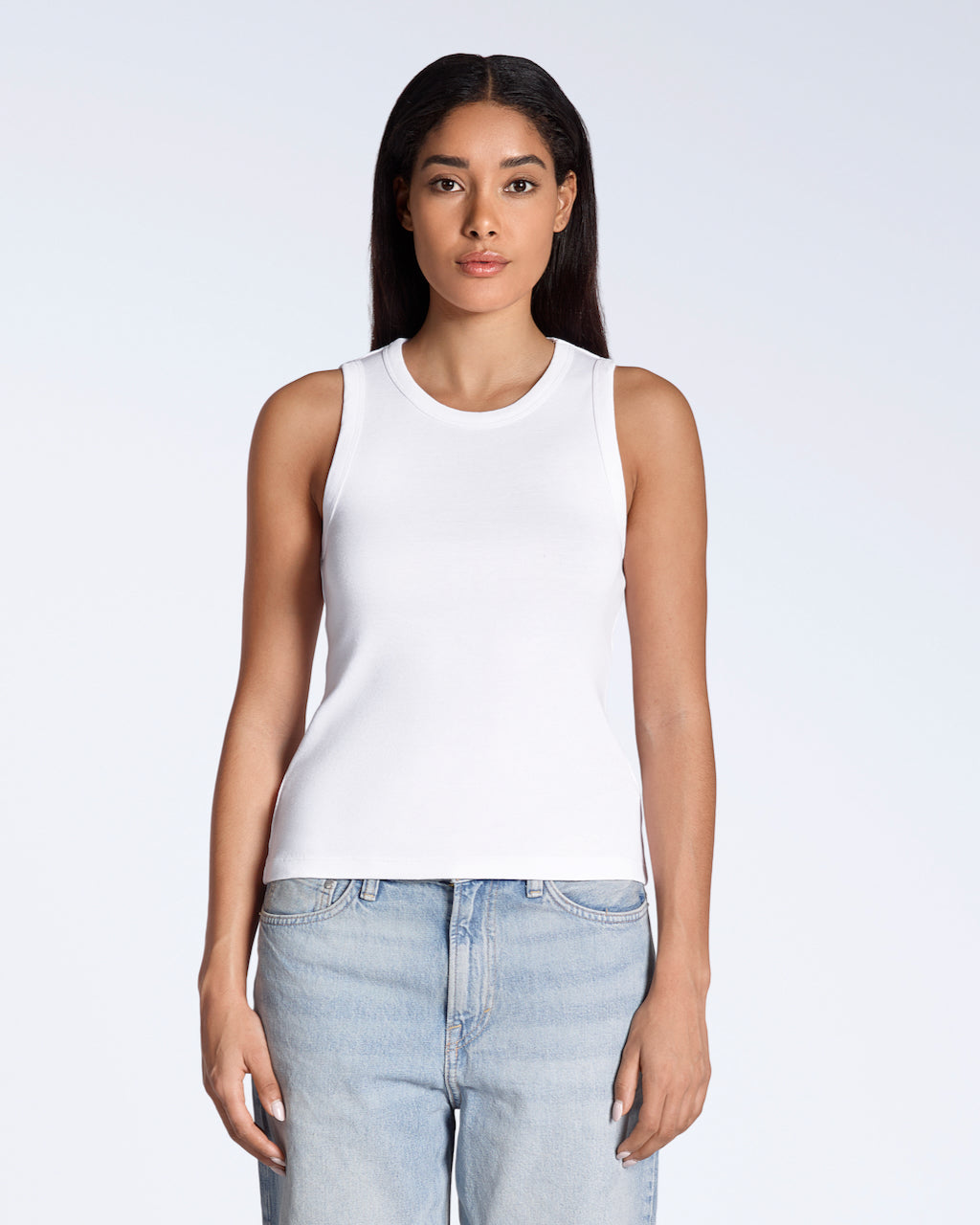 A woman facing front on looking into the camera, modelling a plain white, organic cotton tank top.