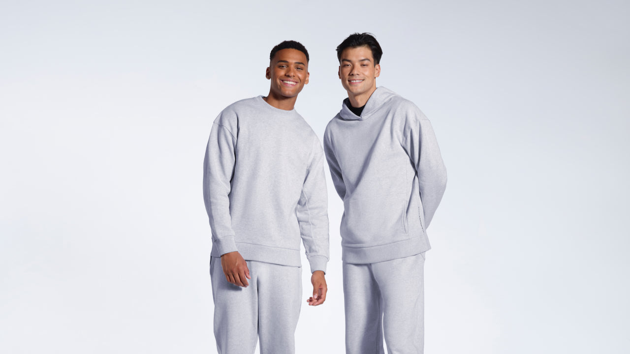 Two men looking into the camera smiling, modelling plain grey heavyweight organic cotton tracksuits.