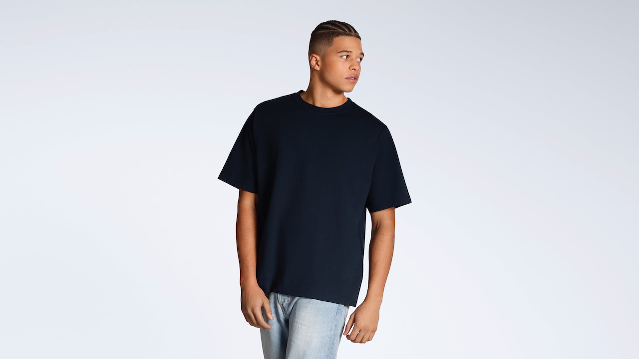 A man looking away from the camera, modelling a plain navy, oversized, organic cotton t shirt.