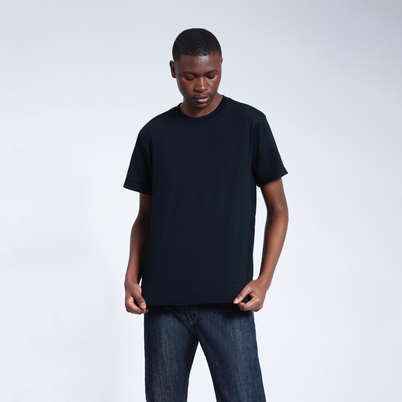 A man looking down, modelling a plain navy short sleeve organic cotton t shirt.