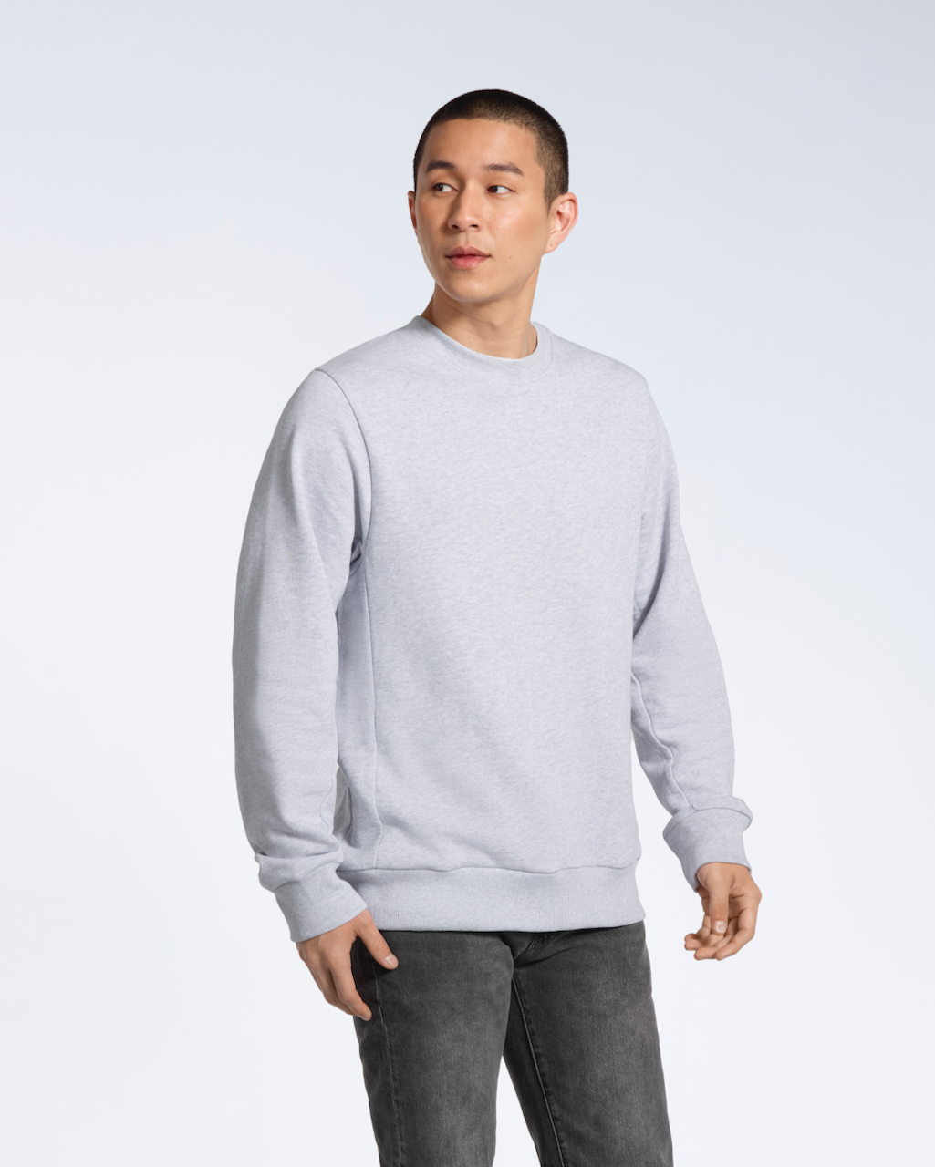 A man looking away from the camera with his arms by his side, modelling a plain grey french terry organic cotton sweatshirt.