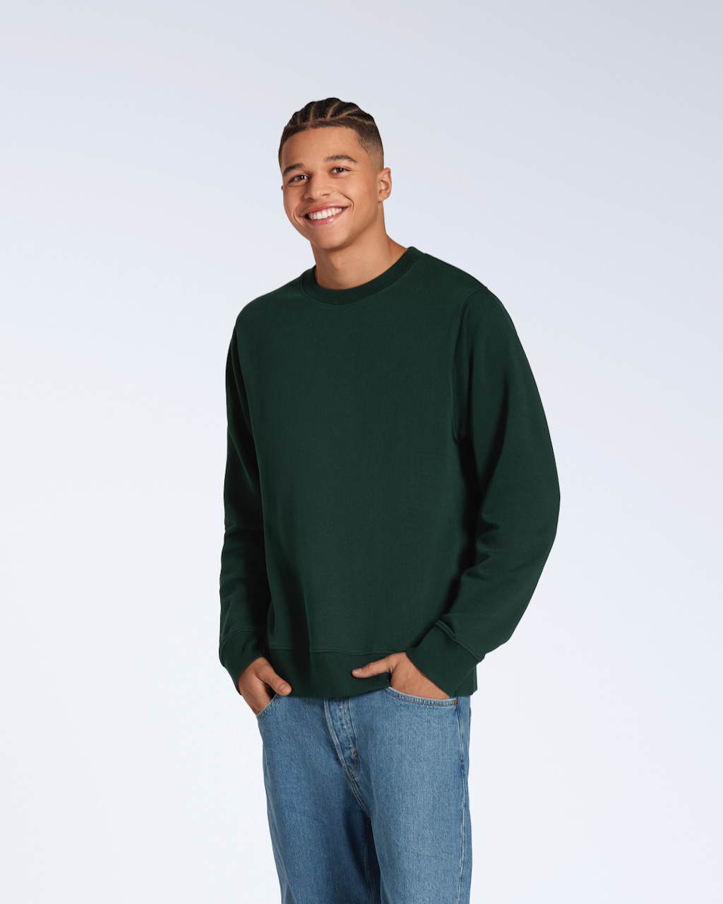 A man smiling into the camera with his hands in his pockets, modelling a plain dark green french terry organic cotton sweatshirt.