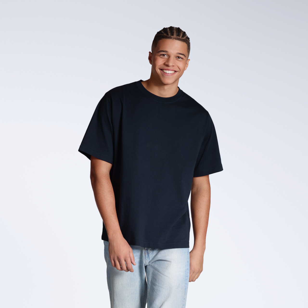 A man smiling, walking towards the camera, modelling a plain navy, oversized, organic cotton t shirt.