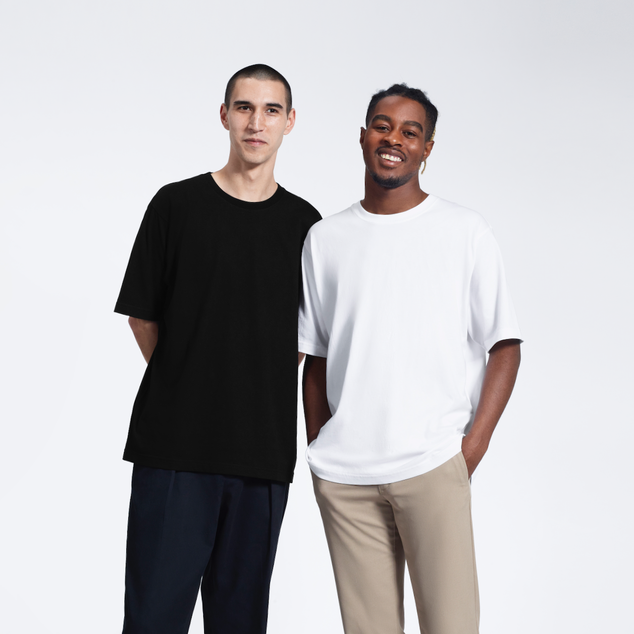 Two men smiling, modelling plain oversized black and white, heavyweight, organic cotton t shirts.
