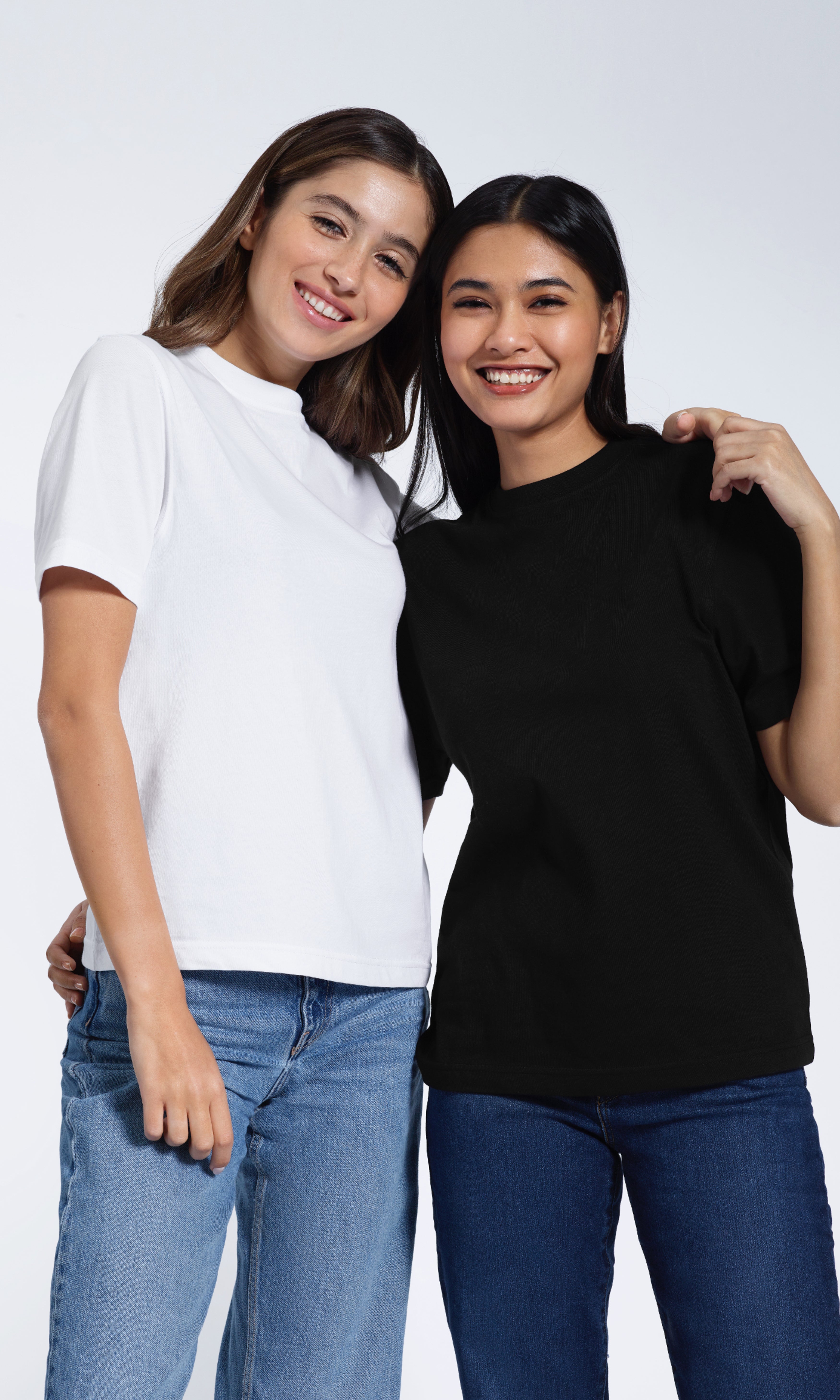 Two women smiling with their arms round eachother, modelling plain white and black organic cotton crew neck t shirts.