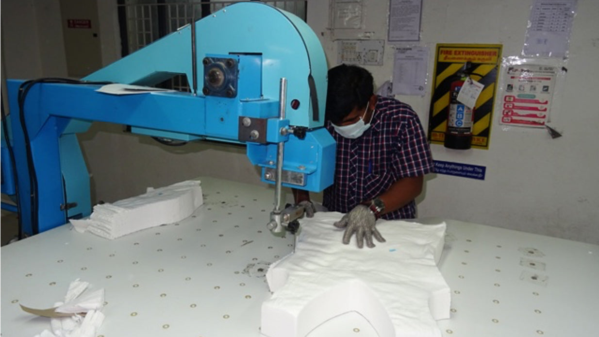 A photo of a factory worker cutting fabric in an ethical factory in India.