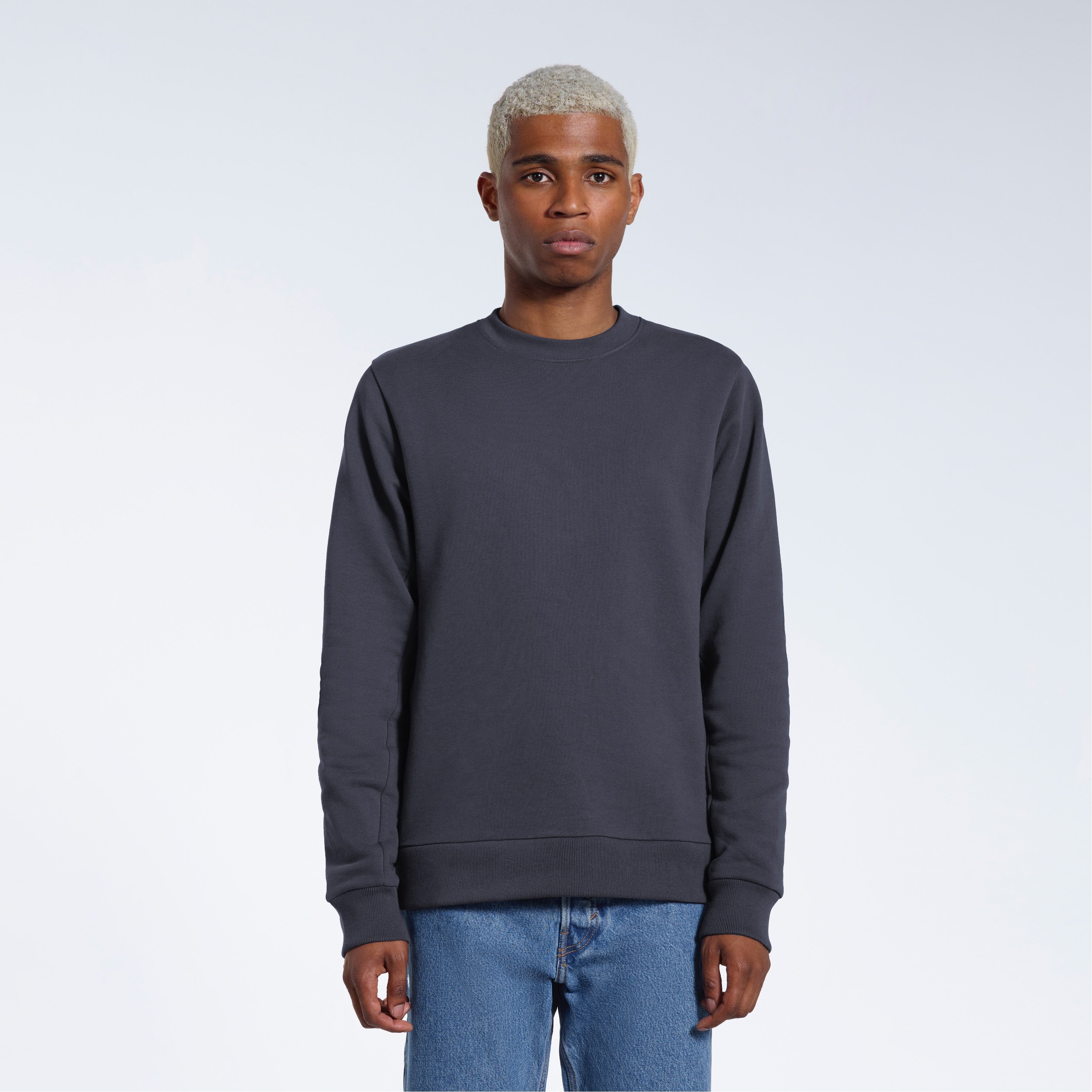 A man face on looking into the camera with his arms by his side, modelling a plain dark grey french terry organic cotton sweatshirt.