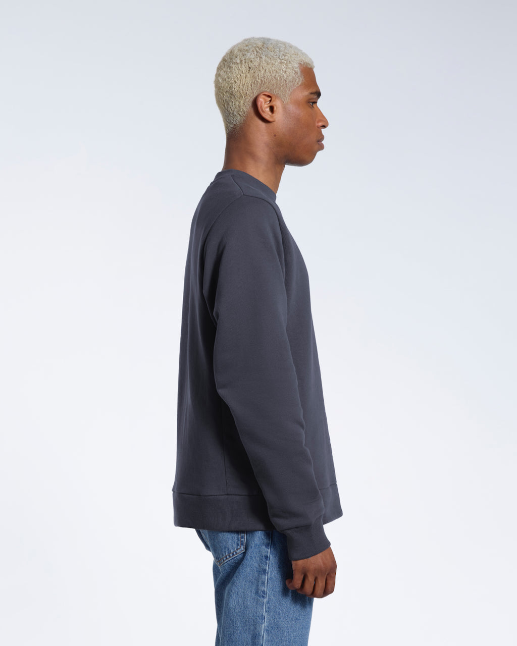 A man facing side on, modelling a plain dark grey french terry organic cotton sweatshirt.