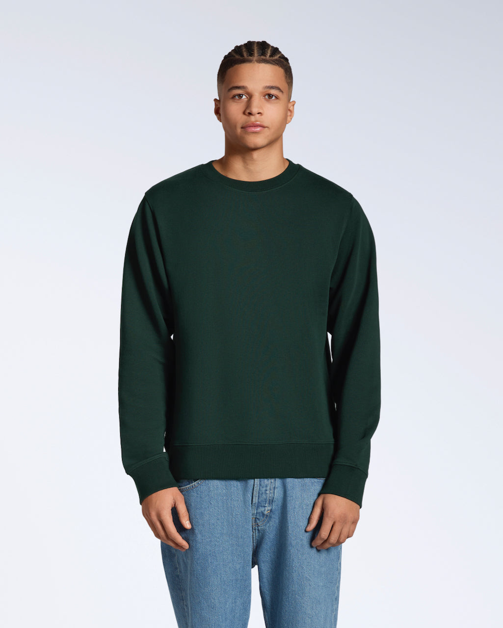 A man face on looking into the camera with his arms by his side, modelling a plain dark green french terry organic cotton sweatshirt.