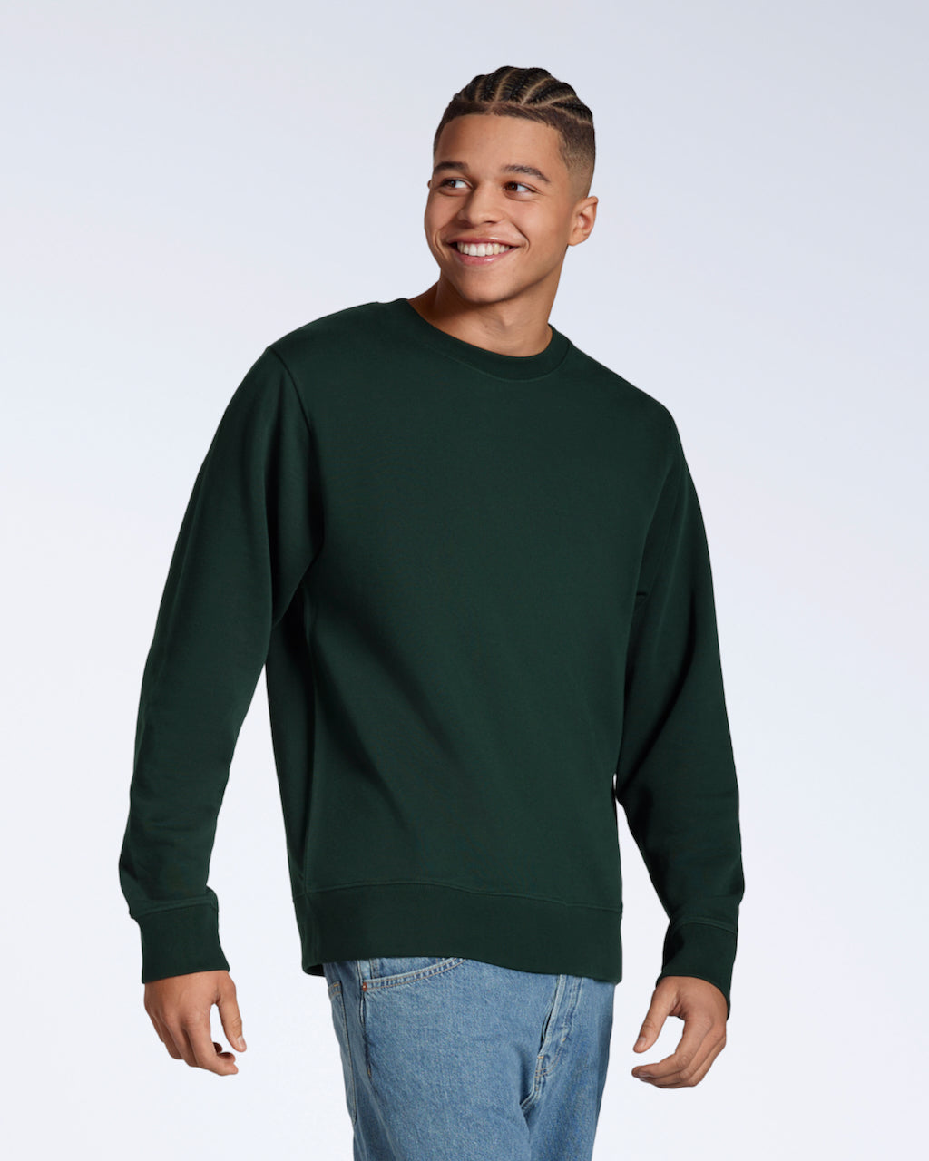 A man smiling, looking away from the camera, modelling a plain dark green french terry organic cotton sweatshirt.