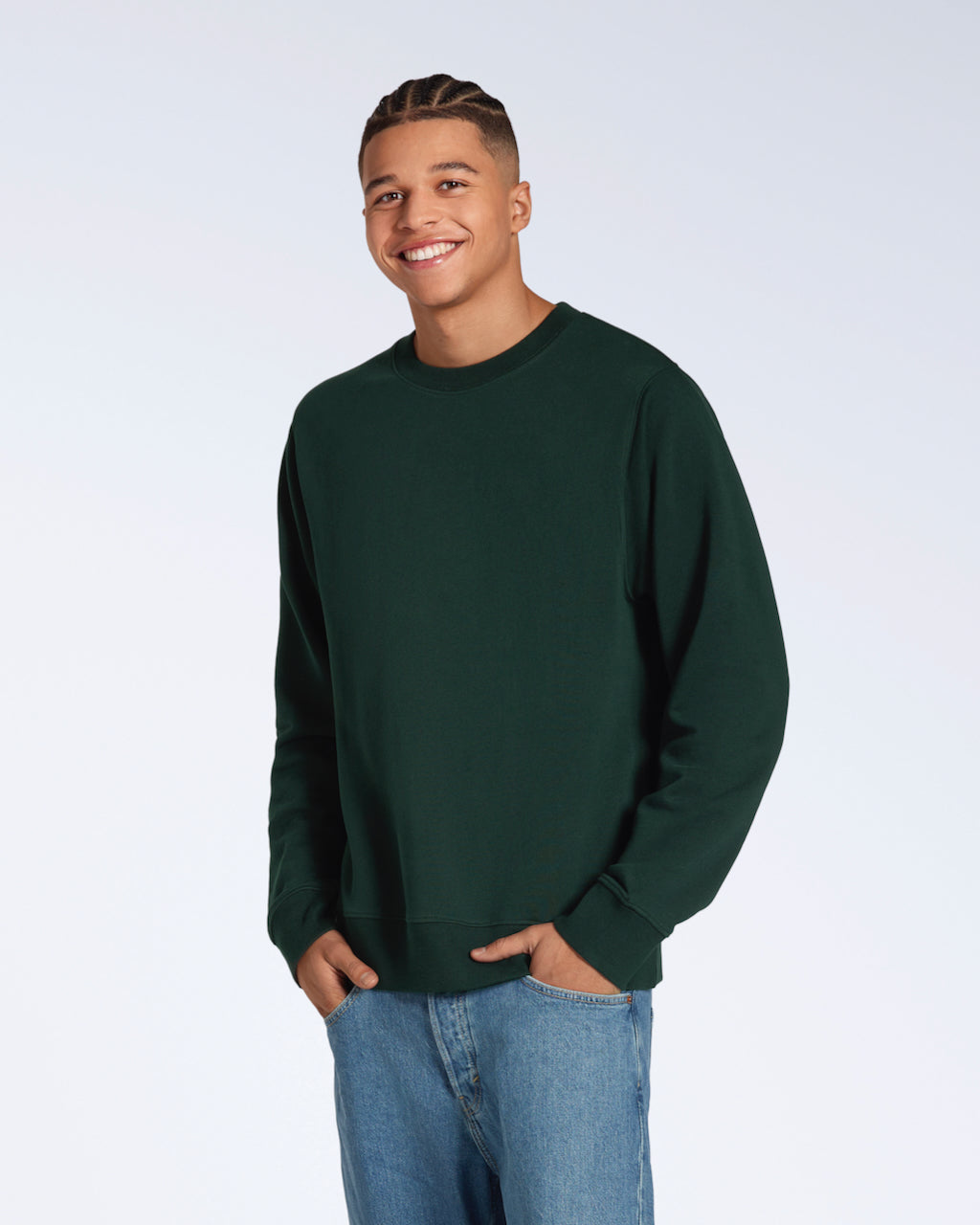 A man smiling into the camera with his hands in his pockets, modelling a plain dark green french terry organic cotton sweatshirt.