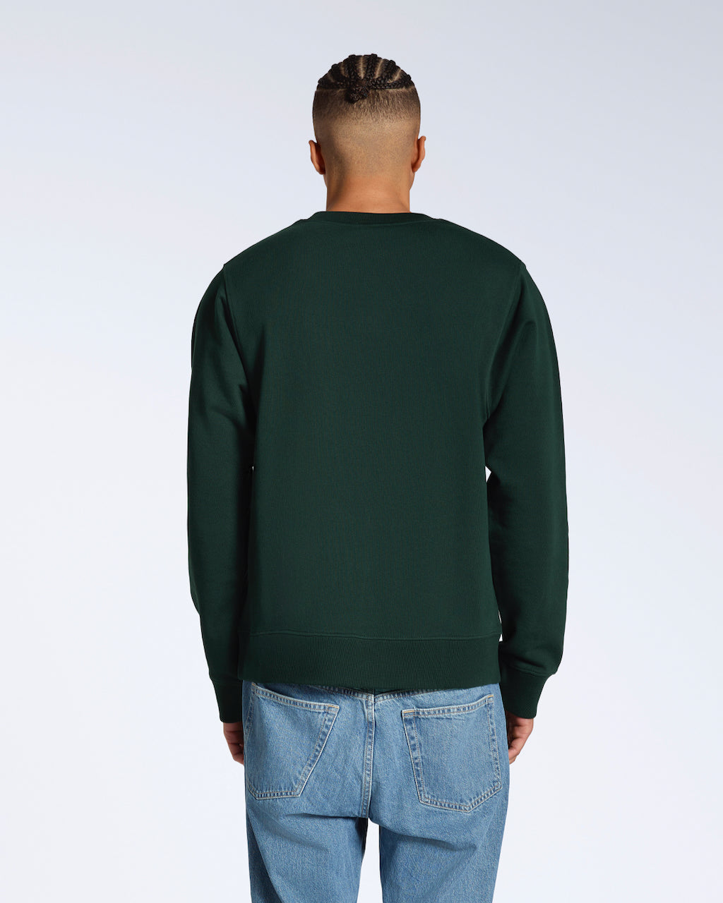 A man facing away from the camera, showing the back of his plain dark green french terry organic cotton sweatshirt.