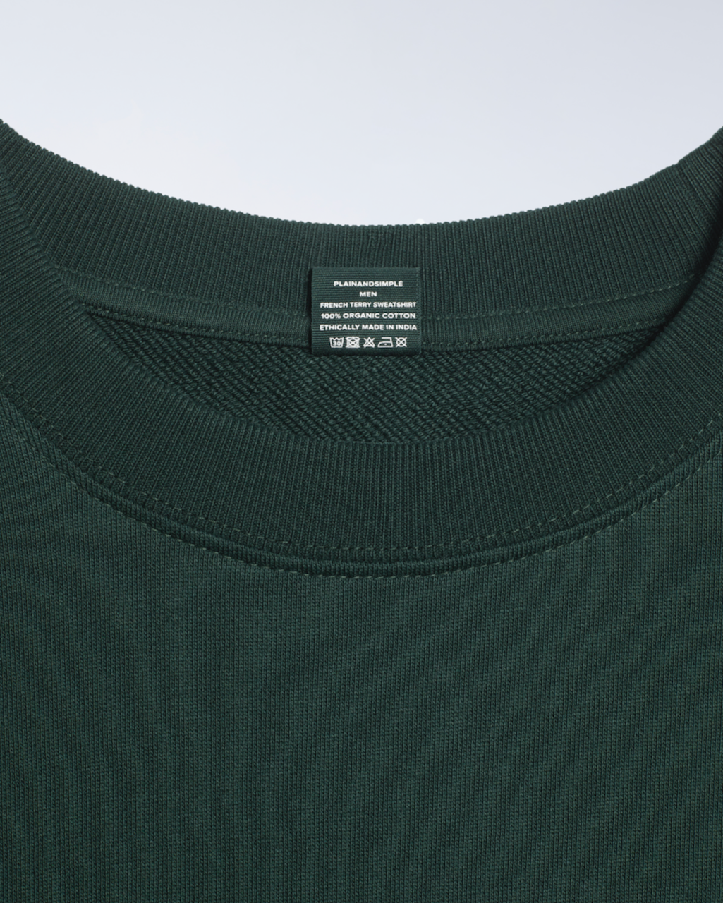 A close up of the neck label in a green, organic cotton sweatshirt.