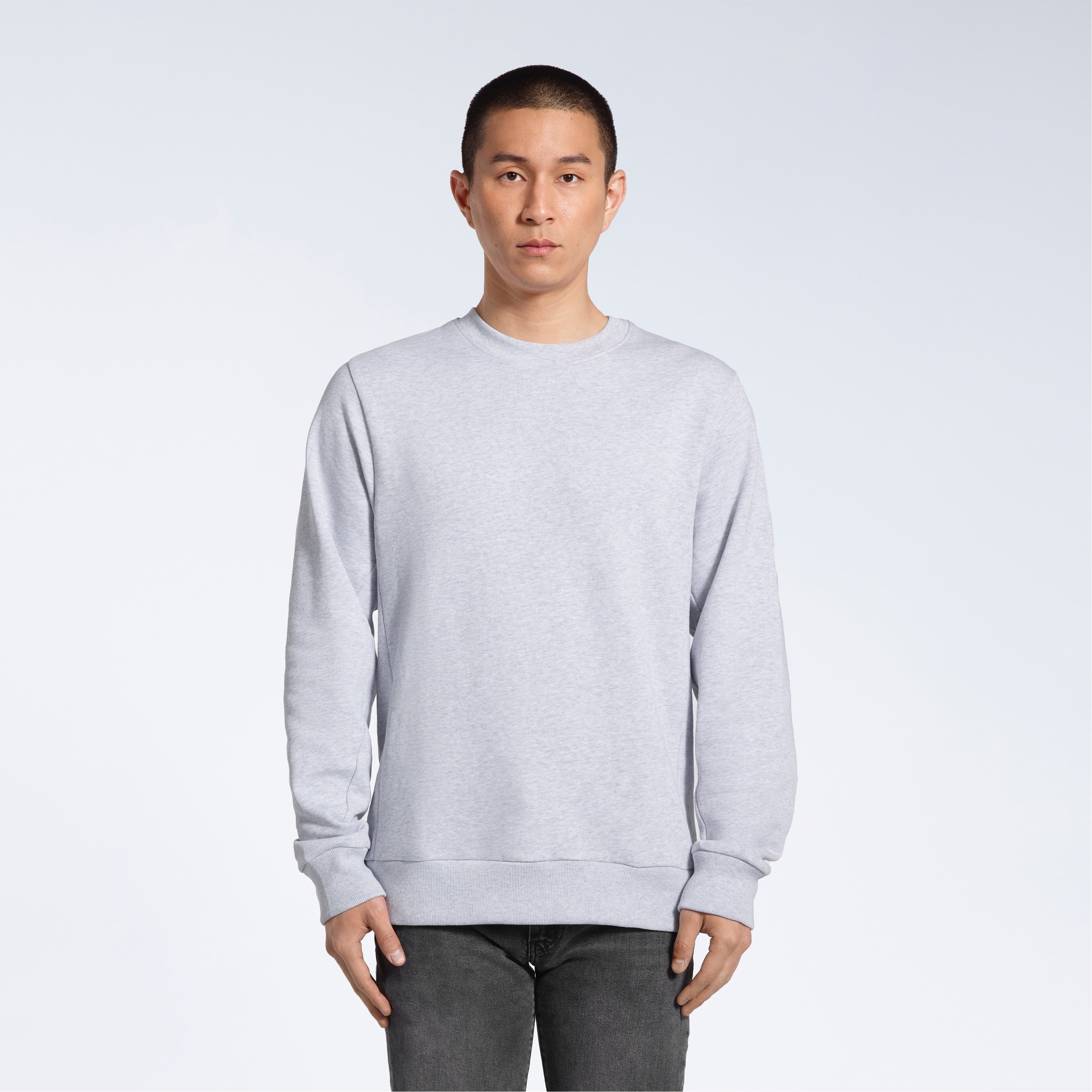 A man face on looking into the camera with his arms by his side, modelling a plain grey french terry organic cotton sweatshirt.