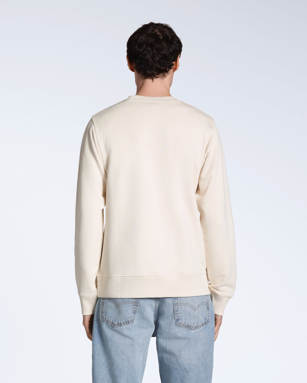 A man facing away from the camera, modelling a plain natural coloured, organic cotton sweatshirt.